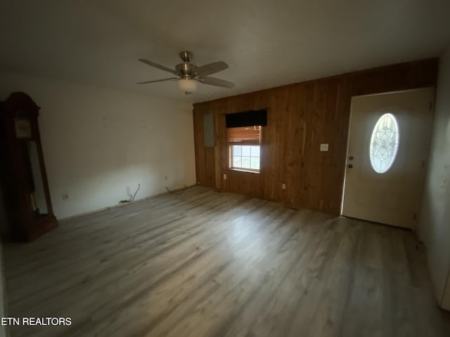 foyer with ceiling fan, hardwood / wood-style floors, and wooden walls