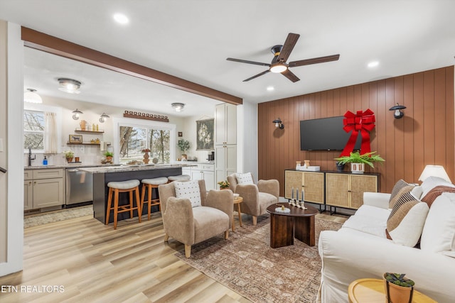 living room with ceiling fan, light wood-type flooring, wood walls, and recessed lighting