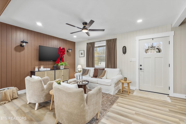 living area with light wood-type flooring, baseboards, and a ceiling fan