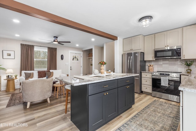 kitchen with light stone counters, stainless steel appliances, backsplash, a kitchen island, and light wood-type flooring