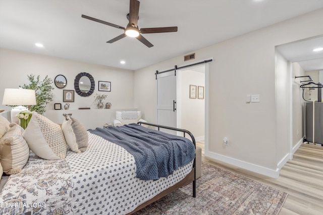 bedroom featuring recessed lighting, light wood-style flooring, baseboards, and a barn door