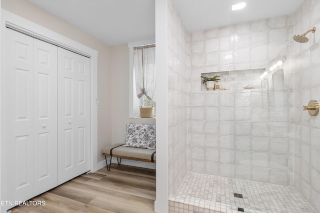 bathroom with a closet, a walk in shower, and wood finished floors