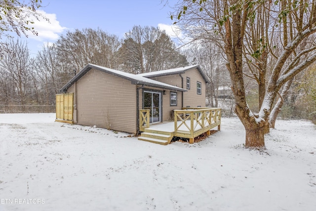 snow covered house with fence and a deck