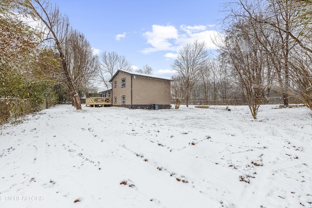 snow covered property with a deck and fence