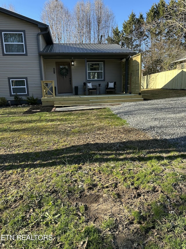 view of front facade featuring fence, metal roof, and a front yard