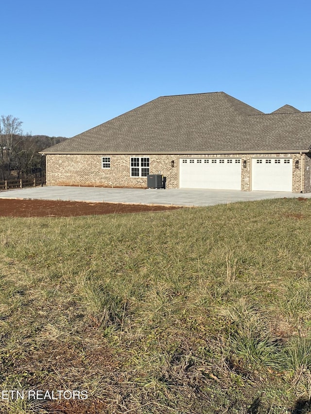 view of home's exterior with a garage, central air condition unit, and a lawn