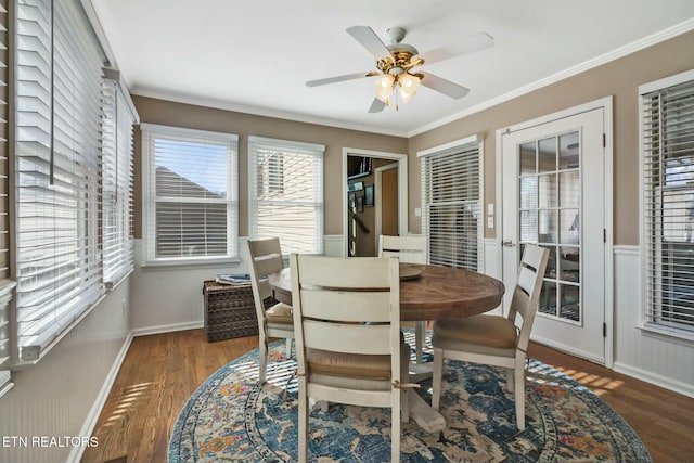 dining space featuring ceiling fan, a healthy amount of sunlight, ornamental molding, and dark wood-type flooring