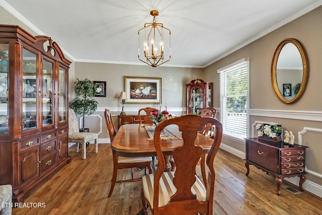 dining room with hardwood / wood-style floors, a notable chandelier, and ornamental molding