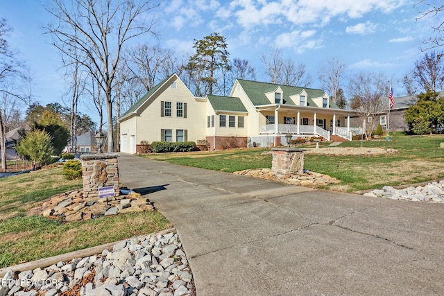 view of front of home with a garage, a porch, and a front lawn