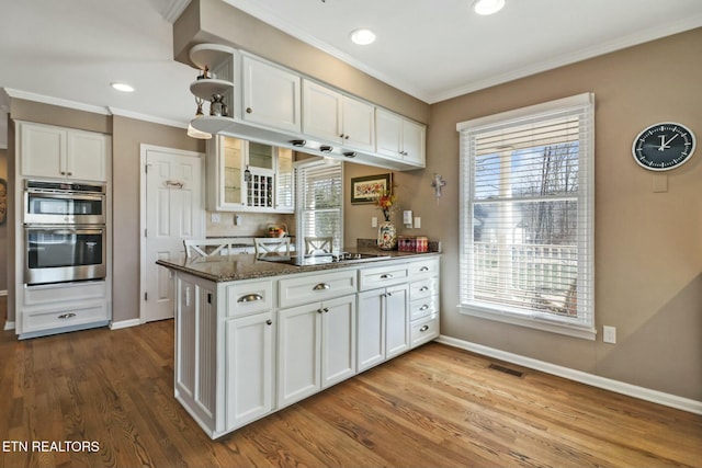 kitchen featuring black electric stovetop, white cabinets, dark stone countertops, kitchen peninsula, and double oven