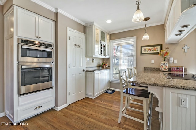 kitchen with stainless steel double oven, white cabinetry, dark hardwood / wood-style flooring, hanging light fixtures, and light stone counters