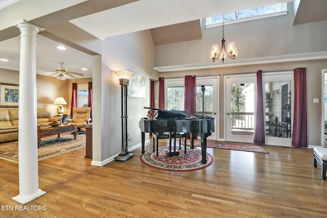 interior space featuring hardwood / wood-style flooring, ceiling fan with notable chandelier, and ornate columns