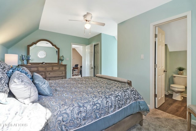 bedroom featuring dark colored carpet, connected bathroom, vaulted ceiling, and ceiling fan