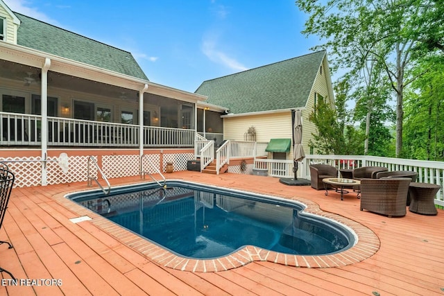 view of pool featuring a wooden deck and a sunroom