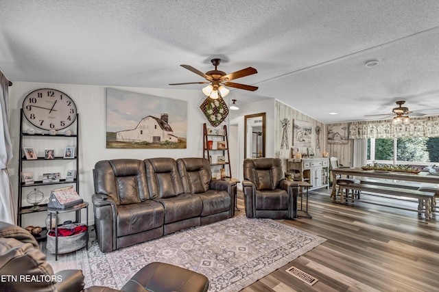 living room with ceiling fan, a textured ceiling, and vaulted ceiling