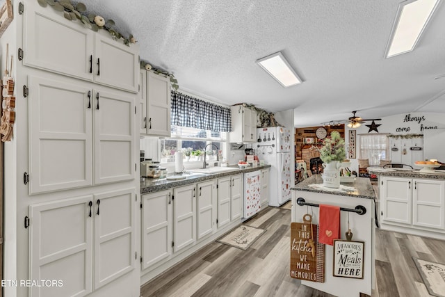 kitchen featuring sink, white cabinetry, white appliances, and a textured ceiling