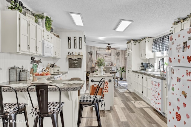 kitchen with white appliances, white cabinets, and a textured ceiling