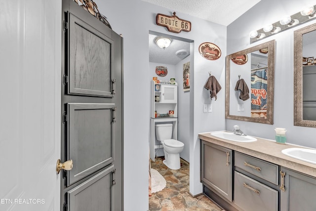 bathroom with a textured ceiling, toilet, and vanity