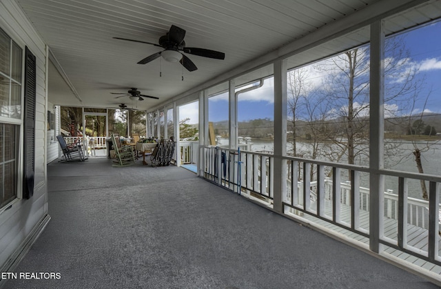 unfurnished sunroom with ceiling fan and a water view