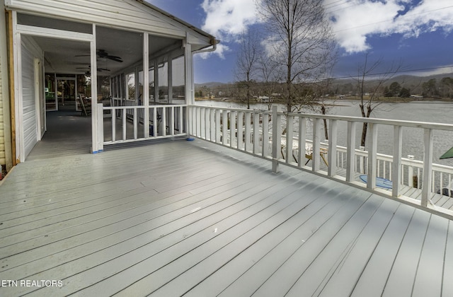 deck with a sunroom, ceiling fan, and a water view