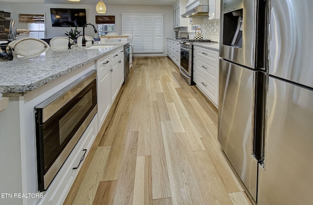 kitchen featuring white cabinetry, sink, wall chimney exhaust hood, stainless steel appliances, and decorative backsplash