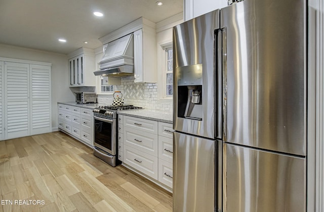 kitchen featuring appliances with stainless steel finishes, white cabinetry, light stone counters, and tasteful backsplash