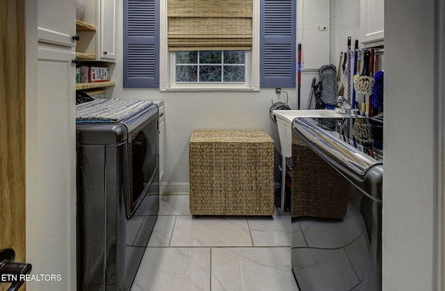 washroom with washer and dryer, cabinets, and light tile patterned flooring