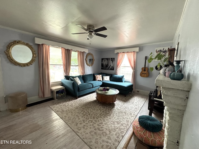 living room with ceiling fan, light wood-type flooring, a stone fireplace, and ornamental molding