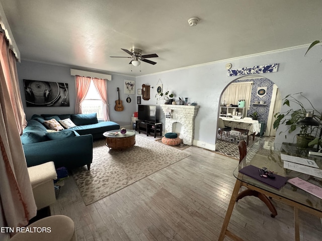 living room with ceiling fan, crown molding, a fireplace, and hardwood / wood-style flooring