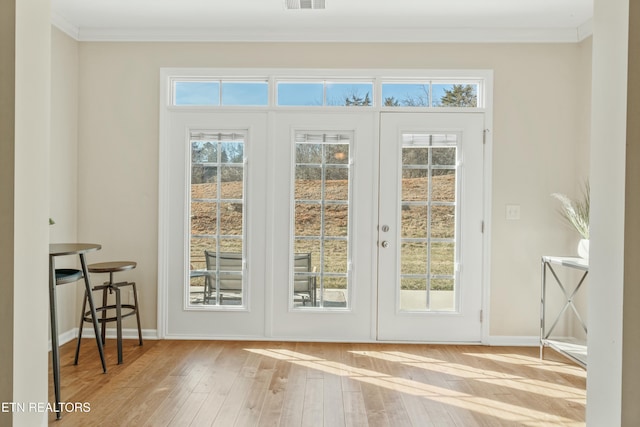 doorway featuring crown molding, light hardwood / wood-style floors, and a wealth of natural light