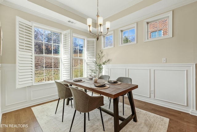 dining area with hardwood / wood-style flooring, plenty of natural light, ornamental molding, and a chandelier