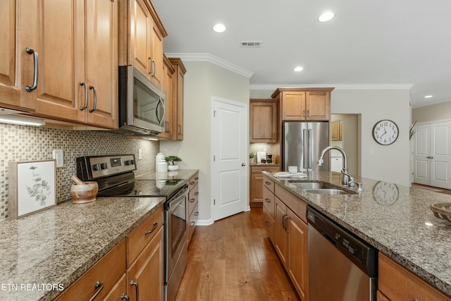 kitchen featuring stone counters, sink, decorative backsplash, ornamental molding, and stainless steel appliances