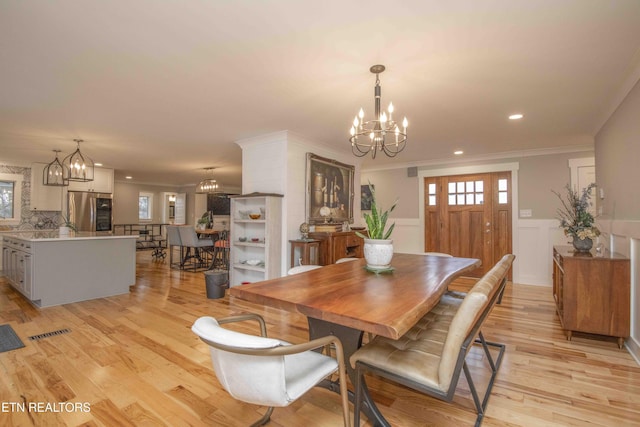 dining room featuring a notable chandelier, ornamental molding, and light hardwood / wood-style flooring