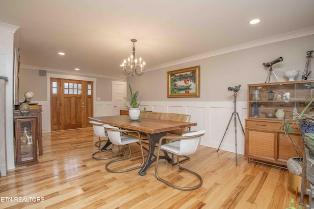 dining area with light hardwood / wood-style floors, an inviting chandelier, and crown molding