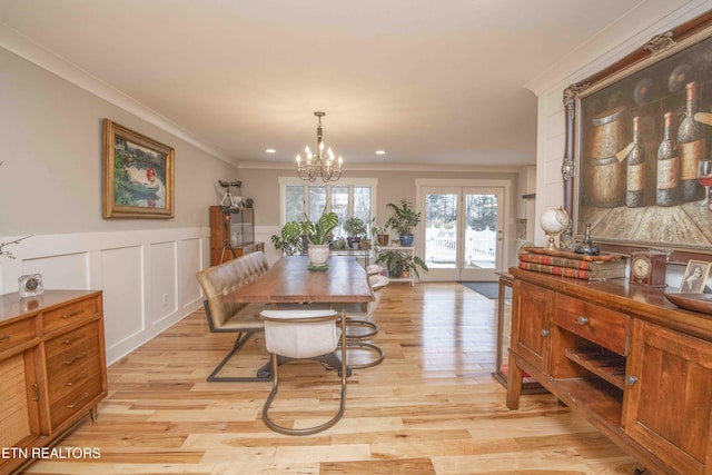 dining space with light hardwood / wood-style flooring, ornamental molding, and an inviting chandelier