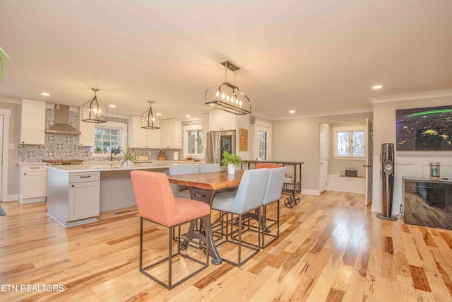 dining room featuring light hardwood / wood-style floors, plenty of natural light, and ornamental molding