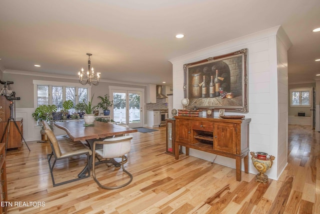 dining room with a notable chandelier, light wood-type flooring, and ornamental molding