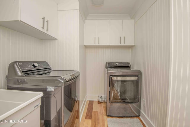 laundry area with cabinets, light hardwood / wood-style floors, washer and clothes dryer, and sink