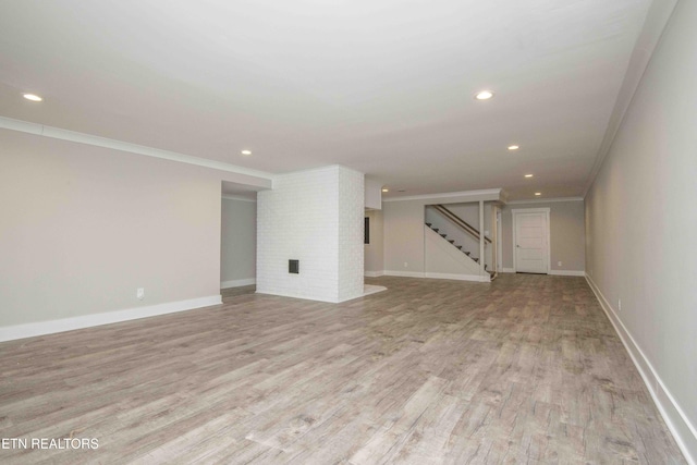 unfurnished living room featuring light wood-type flooring and ornamental molding