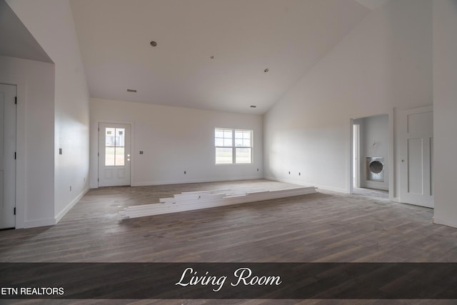 unfurnished living room featuring hardwood / wood-style floors, washer / clothes dryer, high vaulted ceiling, and a wealth of natural light