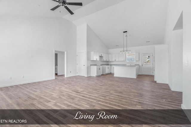 unfurnished living room with high vaulted ceiling, ceiling fan, light wood-style flooring, and baseboards