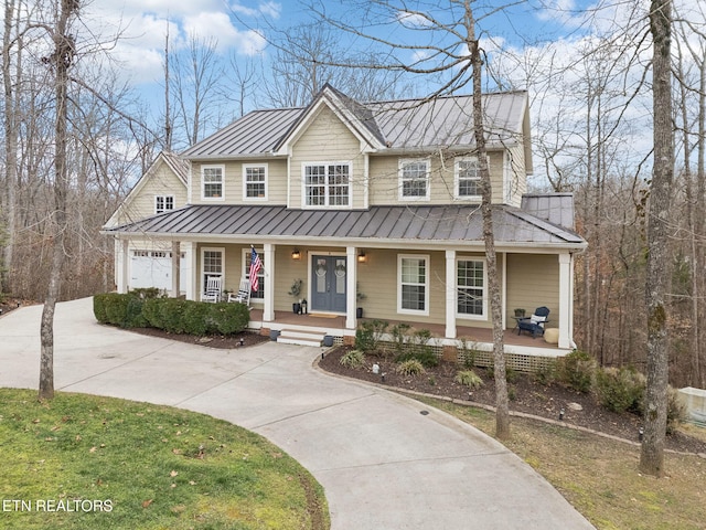 view of front of home featuring covered porch, a garage, and a front lawn