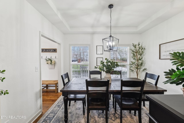 dining area featuring a tray ceiling, hardwood / wood-style flooring, and a notable chandelier