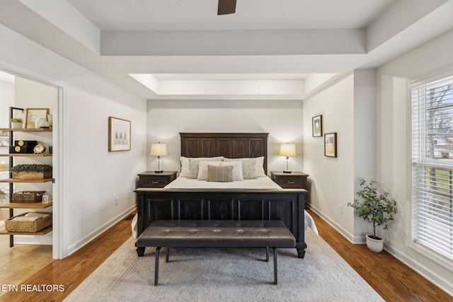 bedroom with hardwood / wood-style floors, a raised ceiling, and ceiling fan