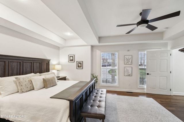 bedroom with a raised ceiling, ceiling fan, and dark hardwood / wood-style floors