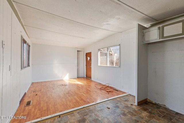 unfurnished room with a textured ceiling and vaulted ceiling