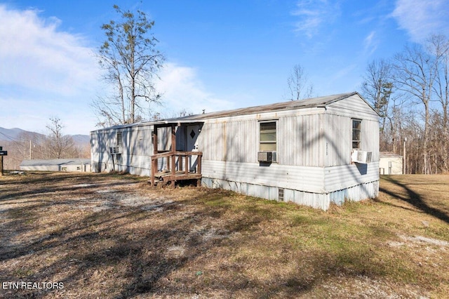 rear view of property featuring a lawn, a mountain view, and cooling unit