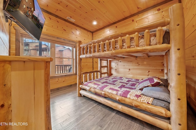 bedroom with hardwood / wood-style floors, wooden ceiling, and wooden walls