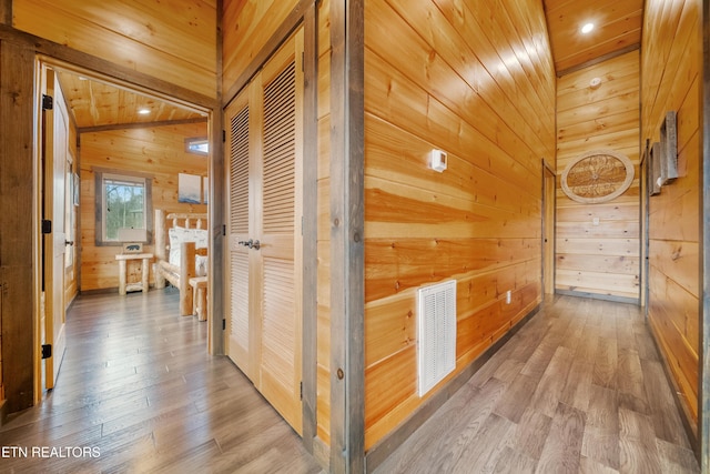 hall featuring wooden walls, hardwood / wood-style floors, and lofted ceiling