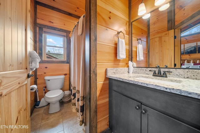 bathroom featuring curtained shower, tile patterned floors, wood walls, toilet, and vanity